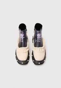 Cream ankle boots with black soles, decorated with pearl beads and a printed portrait of a girl on the front panel.