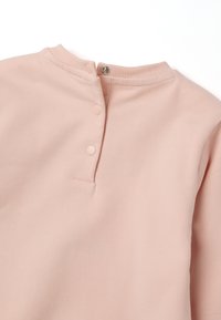 Haut à manches longues rose clair en coton doux. Présente un col à côtes et deux boutons-pression au dos, avec une texture lisse.