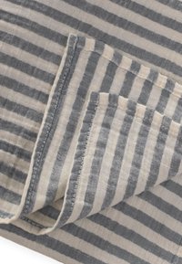 Črtasta bombažna tkanina z izmeničnimi svetlo sivimi in off-white črtami, ki ima mehko, teksturirano površino in skrbno šivane robove.