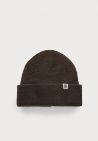 Brown ribbed knit beanie with a folded cuff and a small white logo tag on the side. Made of soft, warm material.