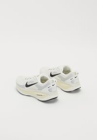 Hvide sportssko med en mesh-overdel, sort Nike swoosh og cremefarvet dæmpning. Har en rund hæl og en struktureret ydersål.