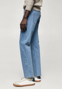 Vaqueros azul claro de pierna recta con un acabado texturizado. Combinados con zapatillas blancas y beige. Incluyen cinco bolsillos y un diseño clásico con trabillas para cinturón.