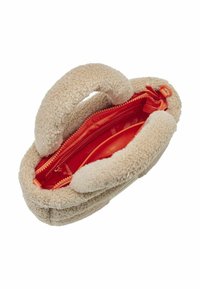 Borsa in pile beige con manici morbidi e arrotondati. L'apertura con zip rivela un interno rosso vivace con una tasca con zip. Esterno testurizzato.