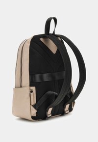 Zaino in pelle beige e rete nera con doppie spalline, un comparto principale con zip e una tasca laterale con zip.