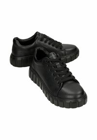 Sneakers neri con tomaia in finta pelle liscia, punta rotonda e suola in gomma spessa con textura rigata e lacci neri a contrasto.