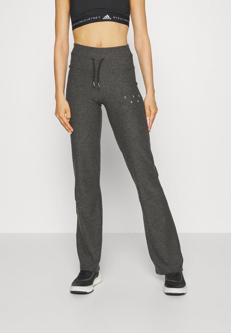 Grå joggers med dragsko i midjan, slim fit och sidfickor. Har tryckt text på höften. Texturerad tyg. Kombinerat med svarta sneakers.