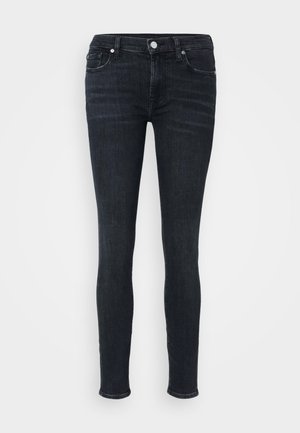 Skinny jeans in dark indigo denim, featuring a mid-rise waist, classic five-pocket design, and subtle stitching details along the seams.