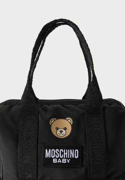 Μαύρη τσάντα Moschino Baby με δύο λαβές, με μικρό πρόσωπο αρκουδάκι και λευκή κεντημένη ετικέτα της μάρκας μπροστά.
