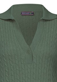 Roheline kootud polo-sweater, millel on kaabeldisain, krae, nupuga sulgemine ja soonikkoed. Kanga struktuur on pehme ja tekstureeritud.