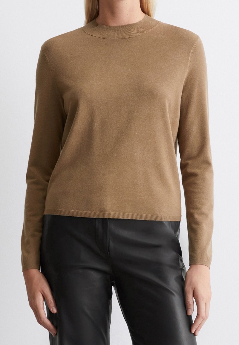 Maglione marrone a maglia con maniche lunghe, collo rotondo e una texture morbida. Abbinato a pantaloni in pelle nera per creare contrasto. Design semplice e minimalista.
