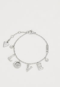 Pulsera de cadena de plata con encantos en forma de letras que dicen "AMOR", un encanto de diseño circular, un acento floral y una etiqueta triangular marcada "GUESS".
