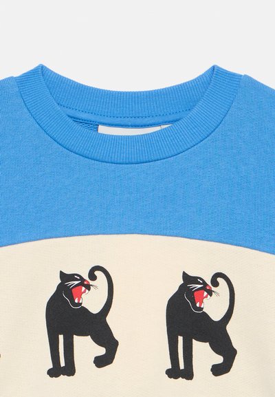 Sweater azul de gola redonda com painel creme, apresentando duas ilustrações de panteras negras, exibindo bocas vermelhas e caudas curvas.