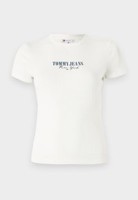 T-shirt blanc à côtes avec un col rond et des manches courtes, comportant un texte "TOMMY JEANS New York" en bleu foncé sur le devant.