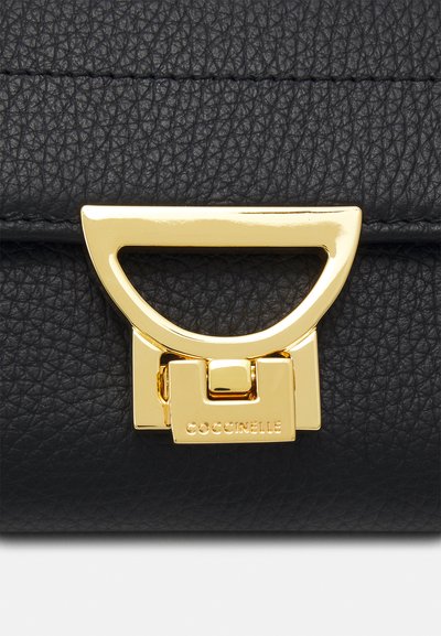 Bolso de mano de cuero negro con textura de guijarros, con un cierre de metal dorado que presenta un diseño geométrico. Logo visible en el cierre.