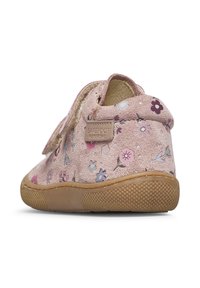 Růžová semišová bota s květinovými vzory, suchým zipem a gumovou podrážkou s texturovaným gripem. Zadní pohled zdůrazňuje měkký, zaoblený tvar.