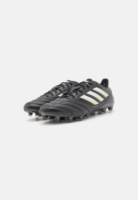 Black leather soccer cleats with yellow and white accent stripes, featuring a low profile, lace-up design, and molded rubber studs.