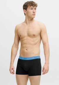 Melnas bokseršortas ar zilu elastīgu jostasvietu, kas rotāta ar „JACK & JONES” logotipu. Mīksta auduma, pieguļoša forma, standarta garums un gluda tekstūra.