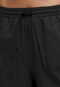 Zwarte, lichte sportshorts met een elastische tailleband en verstelbare trekkoord. Gave textuur zonder zichtbare patronen of hardware.