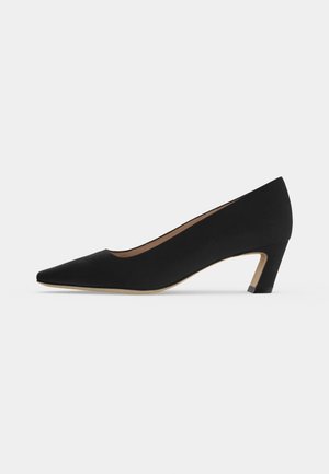Escarpin noir à talon bas avec bout pointu, finition lisse et semelle beige, vu de profil sur un fond clair uni.