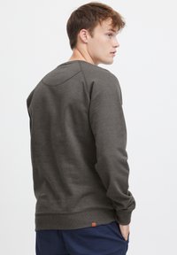 Mørkegrå sweatshirt med rund halsudskæring og raglanærmer, med ribbede manchetter og kant, lavet af et blødt, tekstureret stof.
