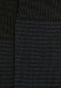Strikket stof med en solid sort tekstur over og vandrette navy-blå og sorte striber nedenunder, med et let hævet mønster.