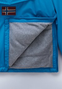 Giacca blu con foderatura in felpa grigia all'interno della tasca con zip. Presenta un patch con un dettaglio bandiera sul lato esterno.