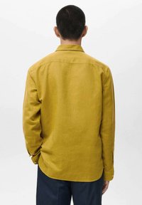 Gelbes Langarmhemd mit Knopfbündchen, geradem Saum und strukturierter Stoffstruktur. Verfügt über eine Rückenpasse und geknöpfte Manschetten.