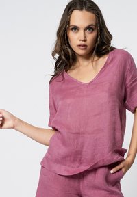 Roze linnen top met een V-hals en korte mouwen, met een relaxte pasvorm en subtiele textuur. Gestyled met bijpassende shorts voor een gecoördineerde look.