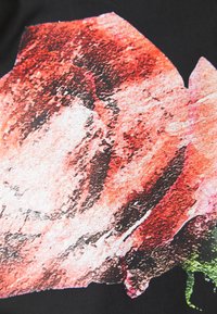 Rood en wit abstract bloemdesign op een zwarte stofbasis, met gestructureerde penseelstreekdetails en kleurverlopen.