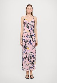 Rožinė maksi suknelė su susiraukšlėjusiu priekiu, plonais petnešėlėmis ir grafiniu raštu juoda, mėlyna ir geltona spalvomis ant lengvos medžiagos.