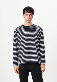 Langermet t-skjorte i marineblå og hvite striper laget av bomull, med rund hals og en liten logo på venstre bryst.