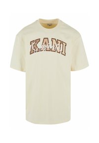 Cream-colored t-shirt with a round neck, short sleeves, and bold brown lettering stating "KANI" with "Originato" in white cursive underneath.
