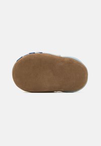 Scarpa azzurra chiara con una suola in suede marrone morbido. Presenta dettagli in gomma e una texture liscia, progettata per il comfort e la stabilità.