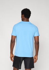 Mænds lyseblå kortærmet t-shirt i blødt stof med rund hals og raglanærmer, parret med sorte shorts.