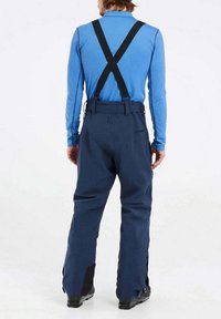 Jūrinės vandeniui atsparios kelnės su reguliuojamais juodais kelniais, laisvas kirpimas ir sustiprinti apatiniai kojų regionai. Lygi tekstūra su kišenėmis gale.