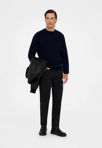 Námornícky sveter, čierna kožená bunda přehozená cez rameno, čierne nohavice a čierne topánky. Jednoduchý dizajn, textúrovaná látka svetra a priliehavý strih.