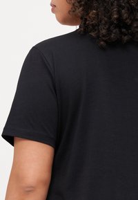 Svart t-skjorte med korte ermer laget av myk bomull, med en avslappet halskant og sømløst skulderdesign, med en jevn tekstur.