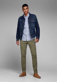 Jeans jakna, svetlo modra srajca z belimi črtami, hlače olivno zelene barve in rjavi Chelsea škornji. Gladek tekstura, prilegajoč se kroj, priložnostni slog.