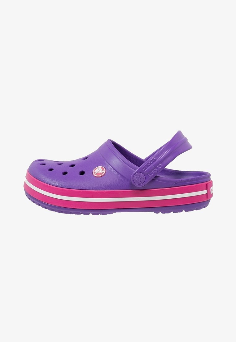 Clog Crocs violet avec une semelle rayée rose et blanche et une sangle arrière ajustable sur fond blanc.