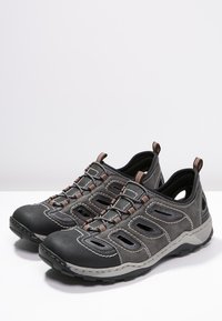 Chaussures d'extérieur grises avec des côtés ouverts, bout en caoutchouc et des coutures contrastées. Dotées d'une semelle durable et d'une languette pour un enfilage facile.