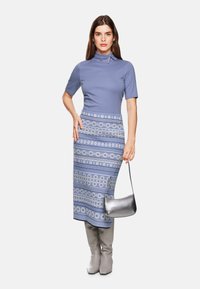 Light blue short-sleeve top with high neck; patterned blue skirt with circular designs; grey knee-high boots; silver handbag.