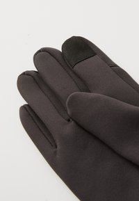 Schwarze Handschuhe aus glattem, flexiblem Material. Merkmale sind ein weicher Touch-Bereich am Daumen und Zeigefinger für die Nutzung von Touchscreens.