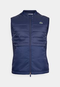 Colete puffer sem mangas em azul-marinho com fecho de correr, painéis frontais texturizados, tecido liso nas laterais e um pequeno logotipo verde no canto superior esquerdo do peito.