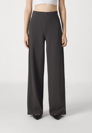 Wide-leg, high-waisted trousers in dark gray fabric. Features smooth texture and side pockets, paired with black pointed-toe shoes.