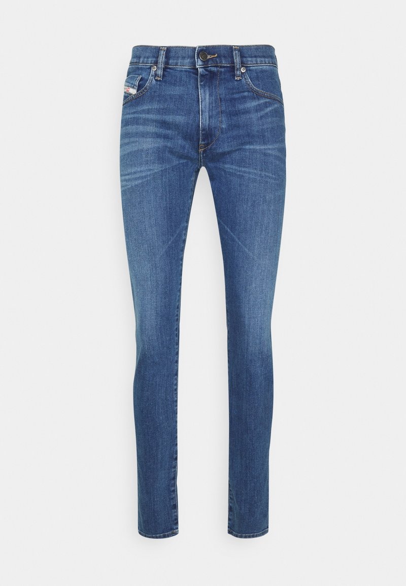 Vaqueros slim fit azul medio con cierre de botón y cremallera, bolsillos en la parte delantera y trasera, y detalles de desgaste sutil en los muslos.