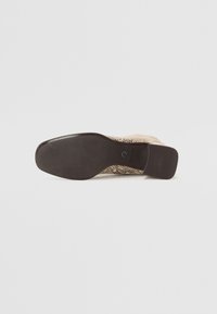 Semelle de chaussure en imitation serpent beige avec un design texturé, dotée d'une plateforme en caoutchouc marron lisse et d'un talon légèrement surélevé.