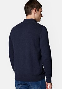 Granatowy, dziany sweter z prążkowanym dołem i mankietami, z wysokim kołnierzem i teksturowanym wzorem na materiale.