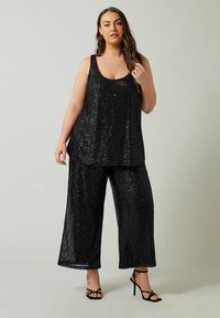 Ensemble composé d'un haut à sequins noirs et d'un pantalon large. Le haut présente un décolleté arrondi, et les deux pièces ont une finition texturée et scintillante.
