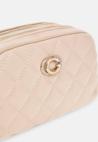 Borsa cosmetica in pelle trapuntata beige con zip in tono oro e accento logo. Presenta un motivo a diamante cucito e una superficie liscia.