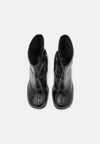 Sorte ankelstøvler med en blank finish i laklæder, med et slankt design, rundet tå og sidelukning med lynlås. Glat tekstur.